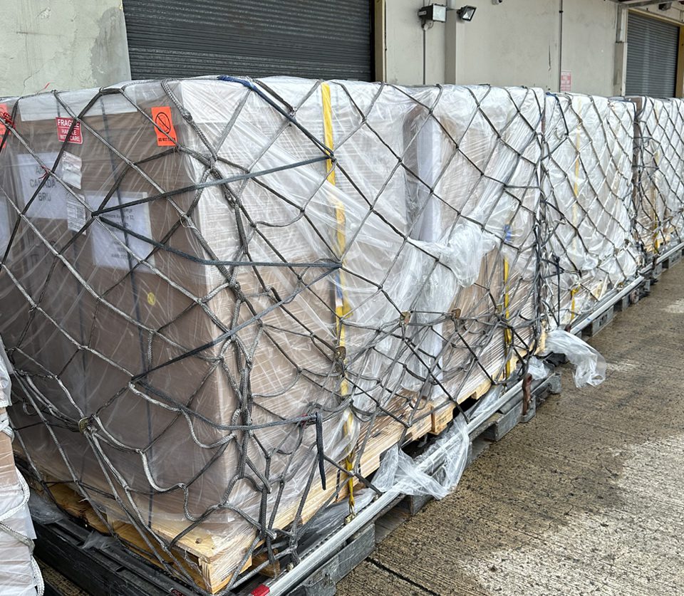 A pallet of boxes wrapped in plastic and tied with string.