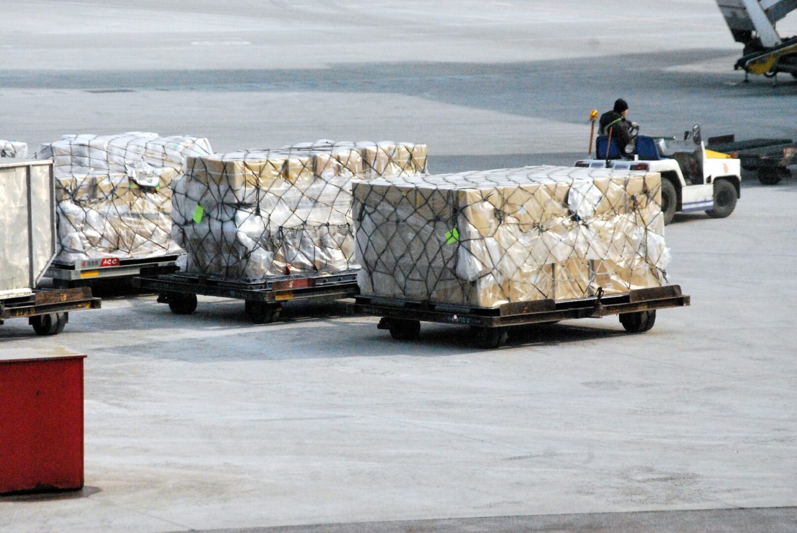 A man riding on the back of a cart with boxes.